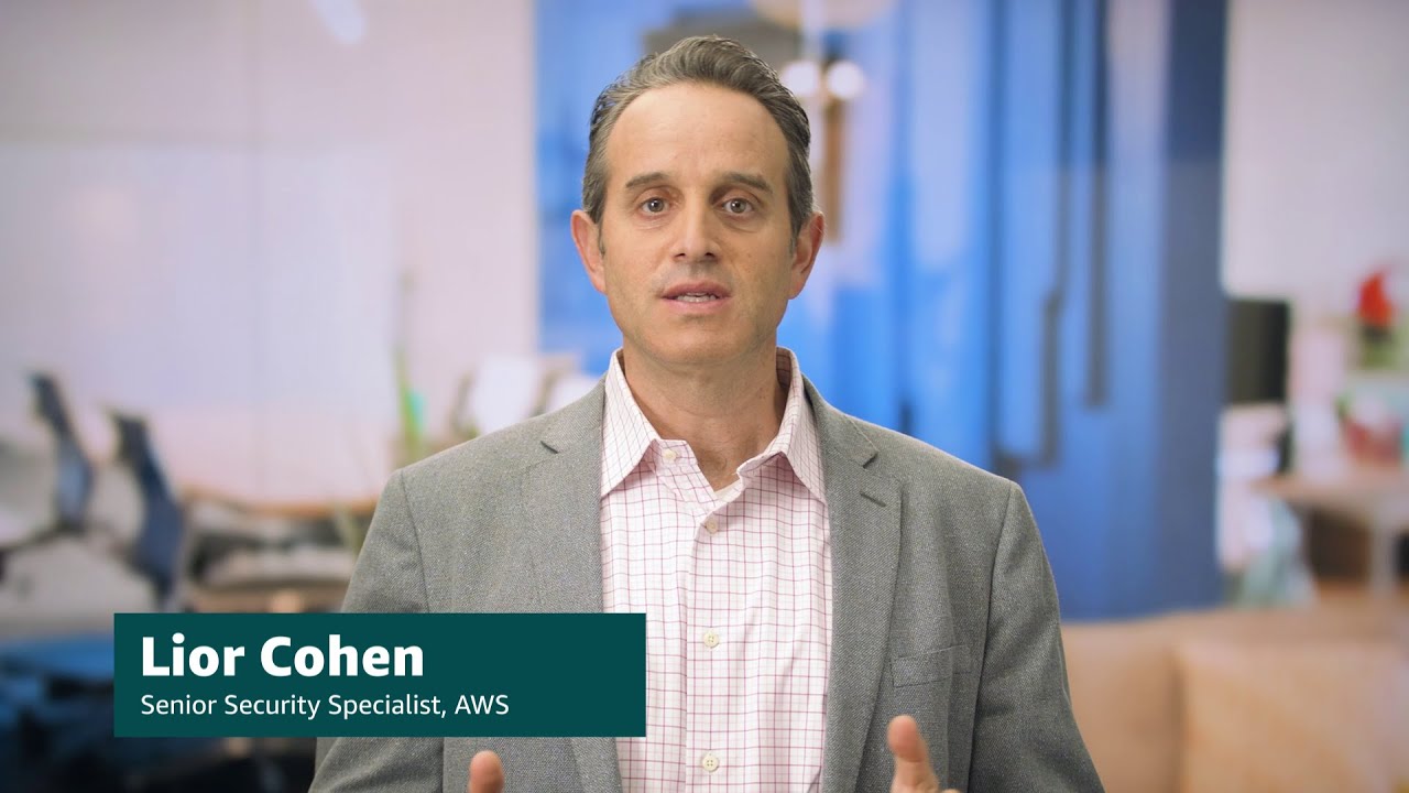 Thumbnail image of Lior Cohen, Senior Security Specialist at AWS, standing in an office environment. The overlay text identifies his name and role, with a blurred background suggesting a professional setting. This image is used for a YouTube video related to AWS security identity and compliance.