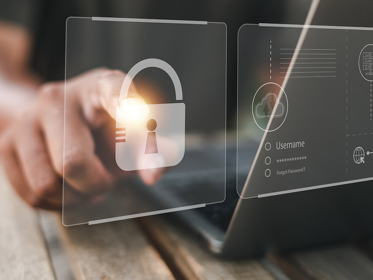 A close-up image of a person interacting with a digital security interface, featuring a large padlock icon and login fields, symbolizing cybersecurity and user authentication on a laptop device.