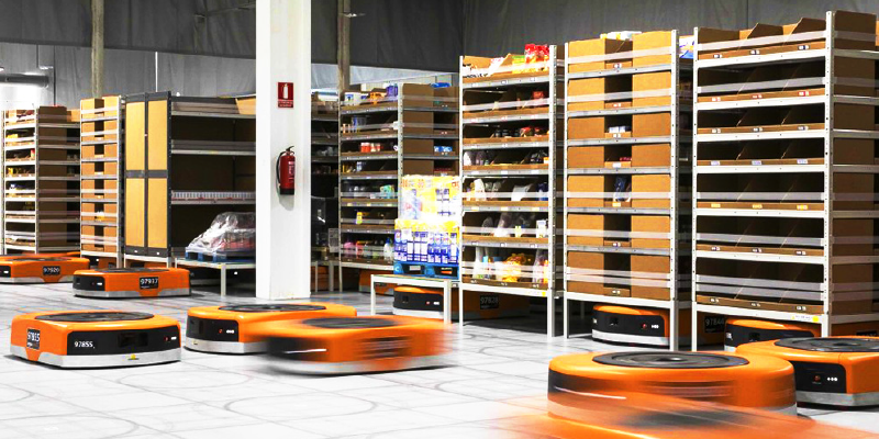 Automated orange robots moving shelves in an Amazon fulfillment center, demonstrating robotics and automation in supply chain logistics.