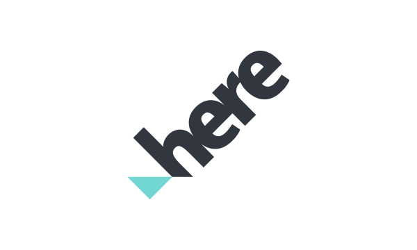 Logo with the word "here" in dark gray, angled diagonally, and a small turquoise triangle beneath the "h".