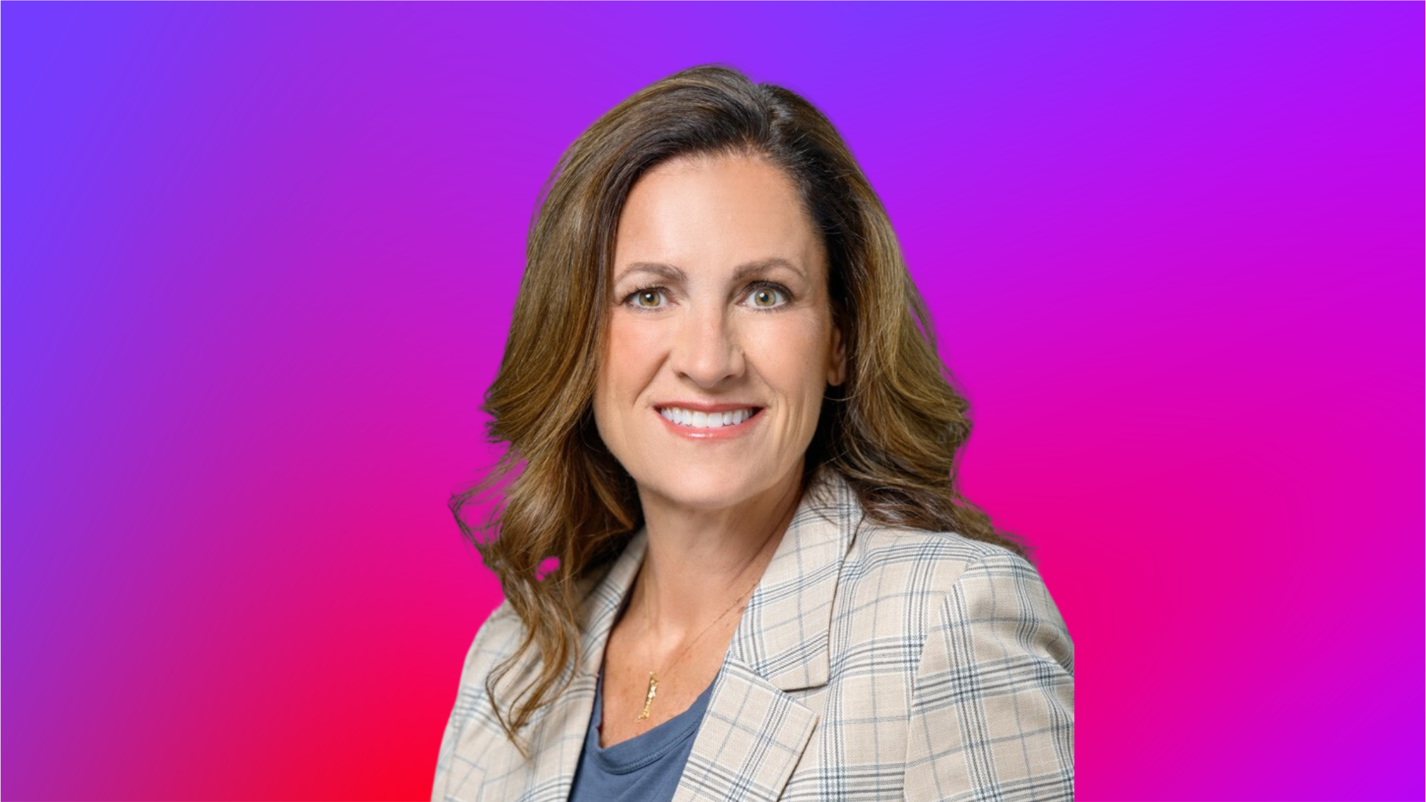 A person with wavy brown hair wearing a plaid blazer and a blue shirt, set against a vibrant gradient background of purple and pink.