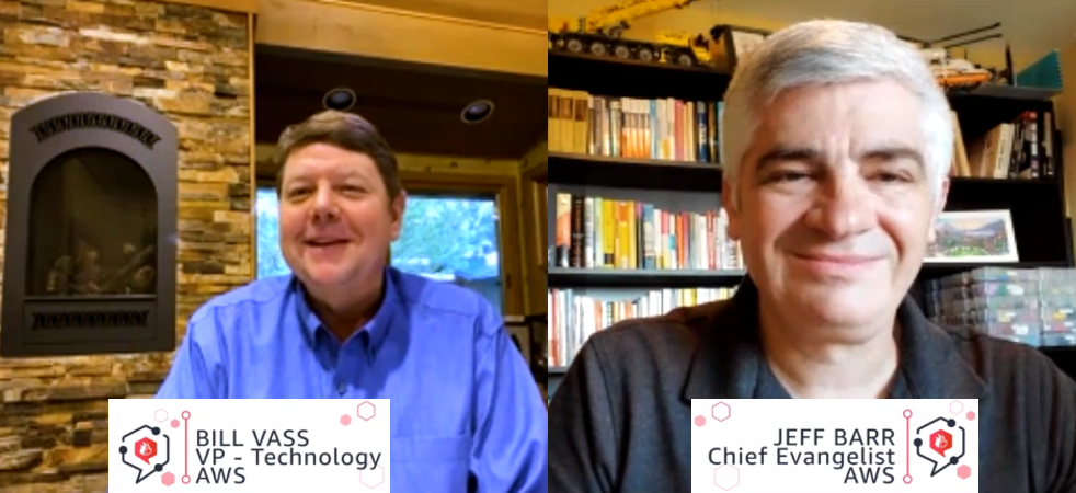 Split-screen video call featuring Bill Vass (VP - Technology, AWS) in a room with a stone fireplace and Jeff Barr (Chief Evangelist, AWS) in a room with bookshelves and model vehicles.