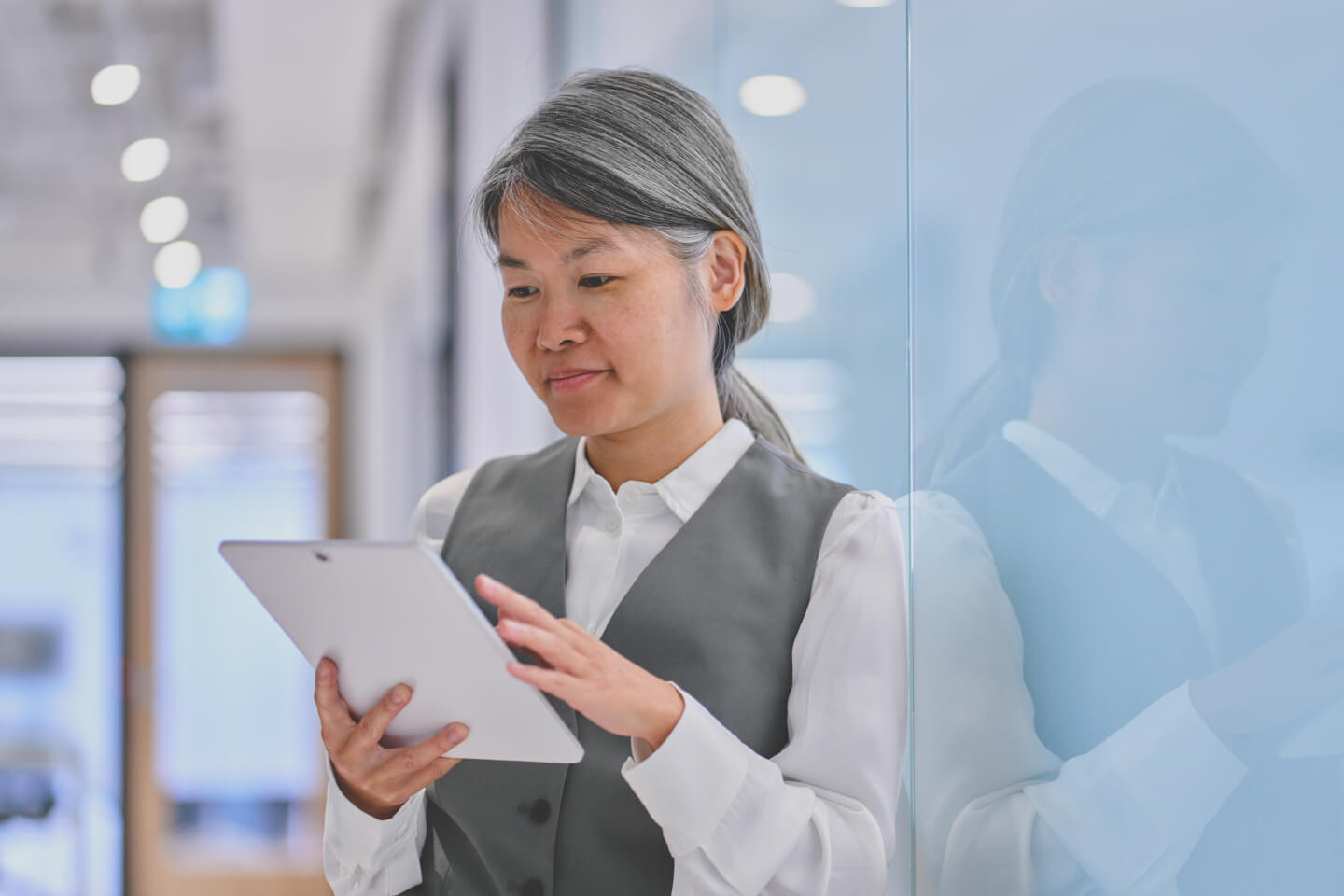 Business decision maker scrolling on tablet device in modern office