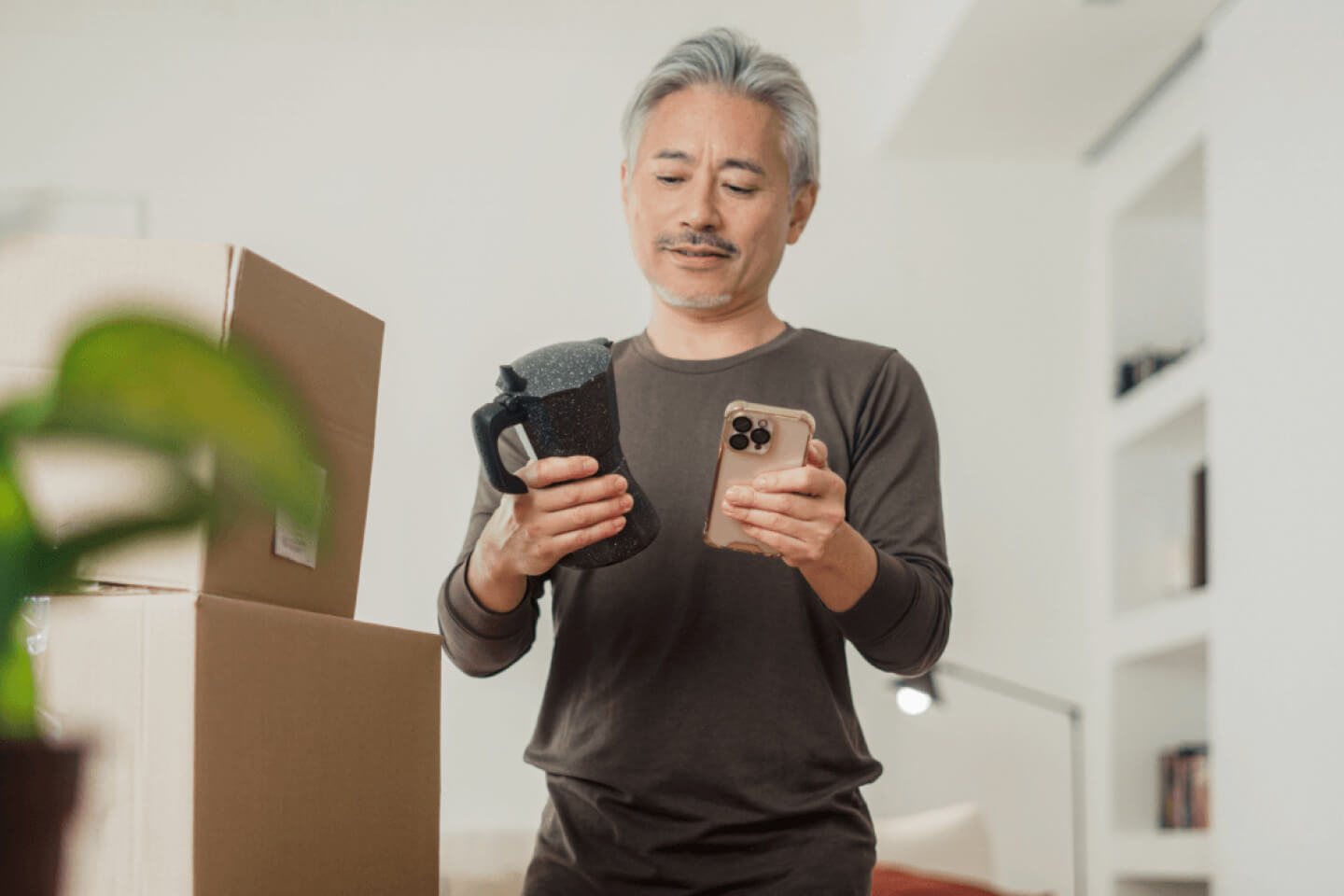 Customer holding moka coffee pot and smartphone next to product delivery parcels