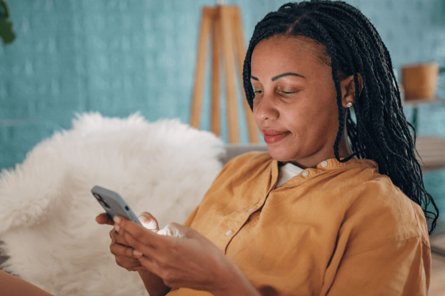 Customer sat on sofa at home looking at smartphone