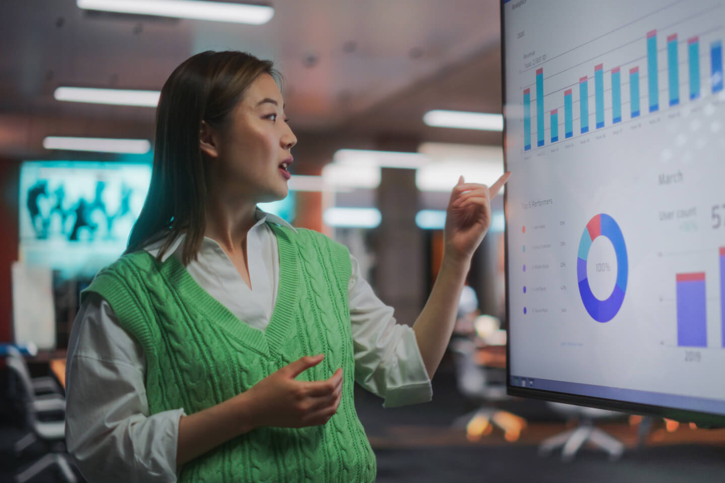 Data analyst pointing at data visualization on large screen 