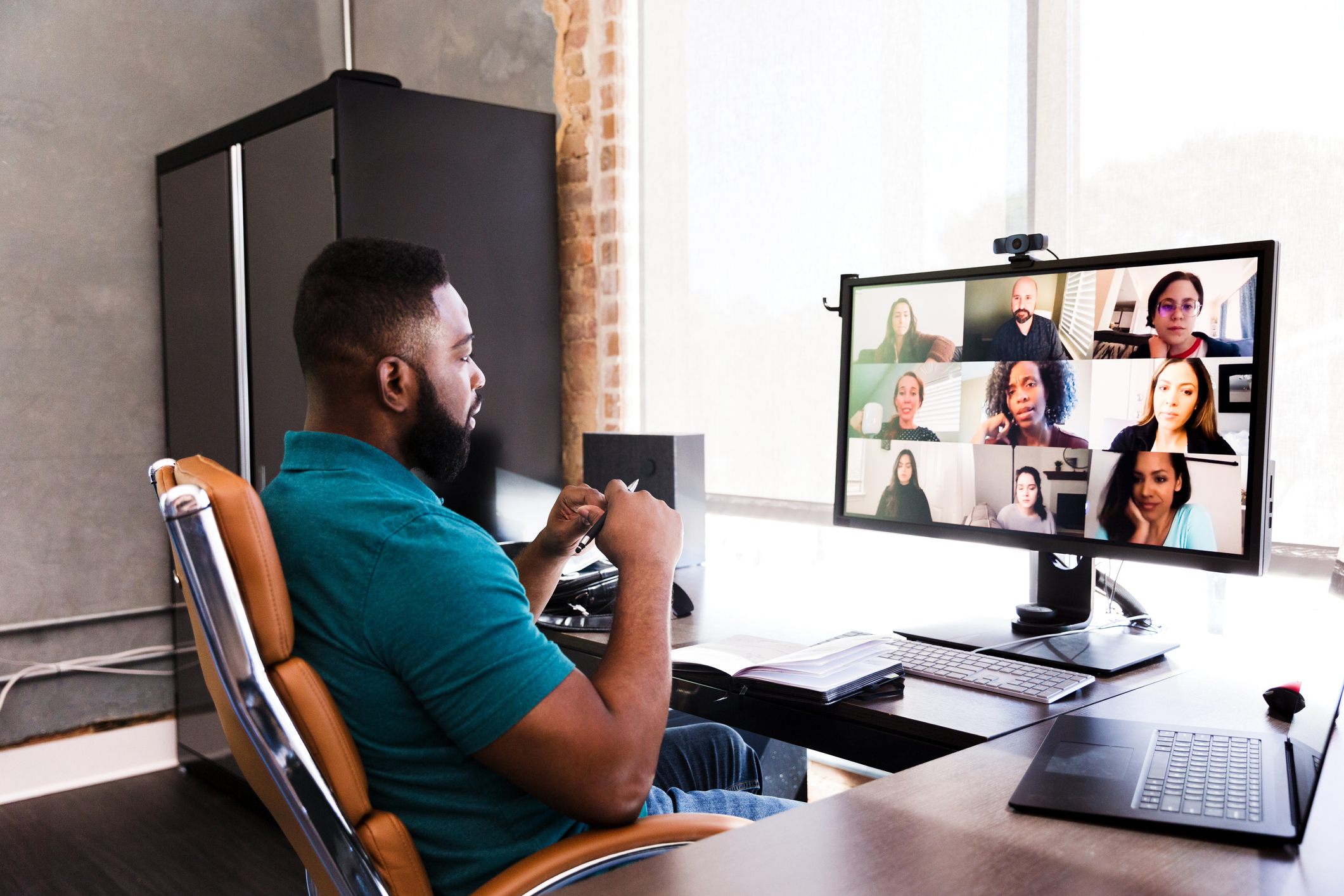 A mid adult man of color video conferences with his team.