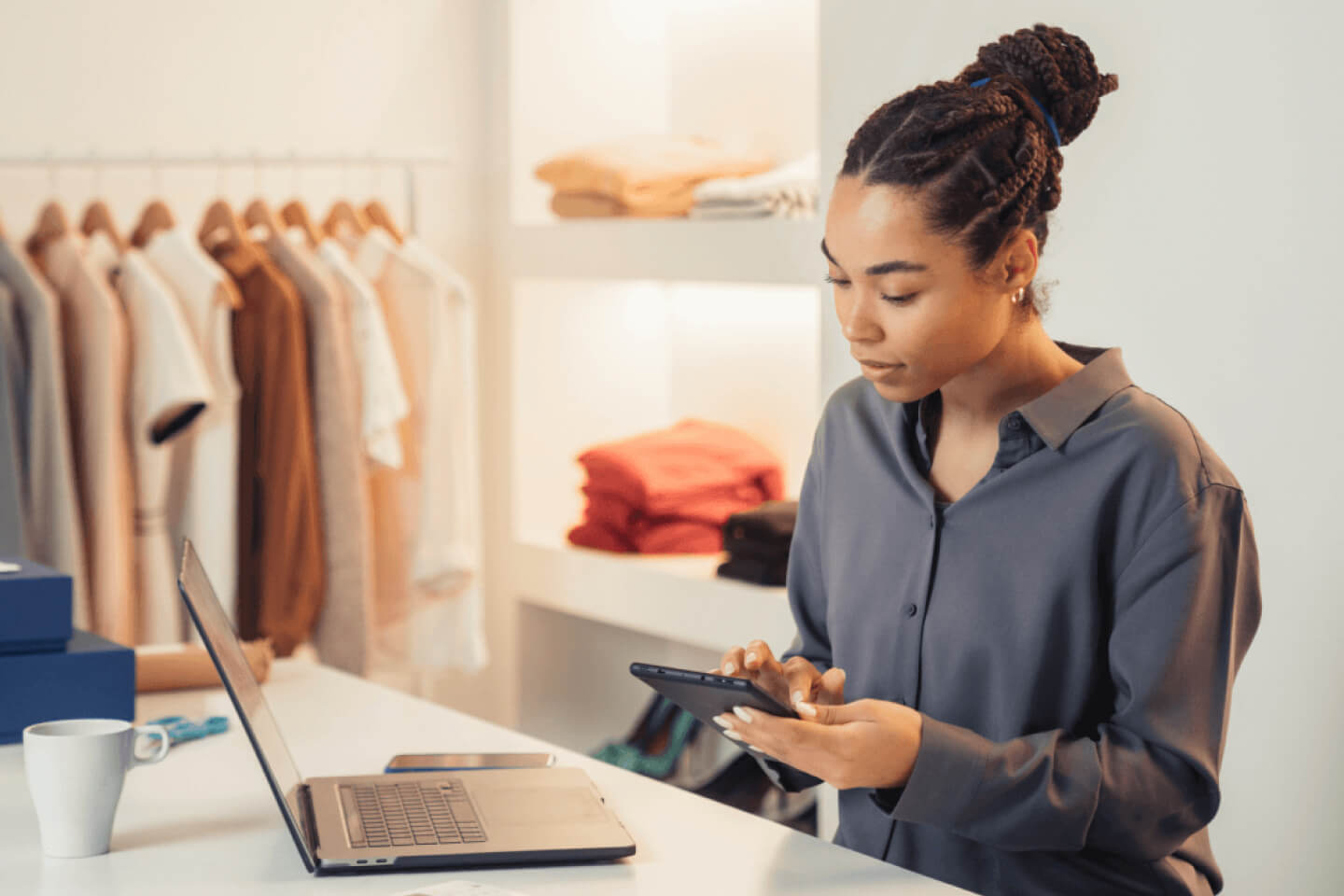 Small business decision maker in retail store in front of laptop holding a smartphone