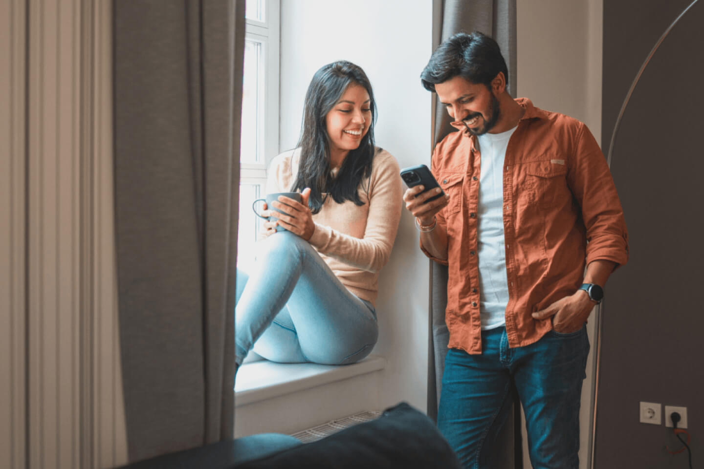 Smiling male and female customers looking at a mobile phone device