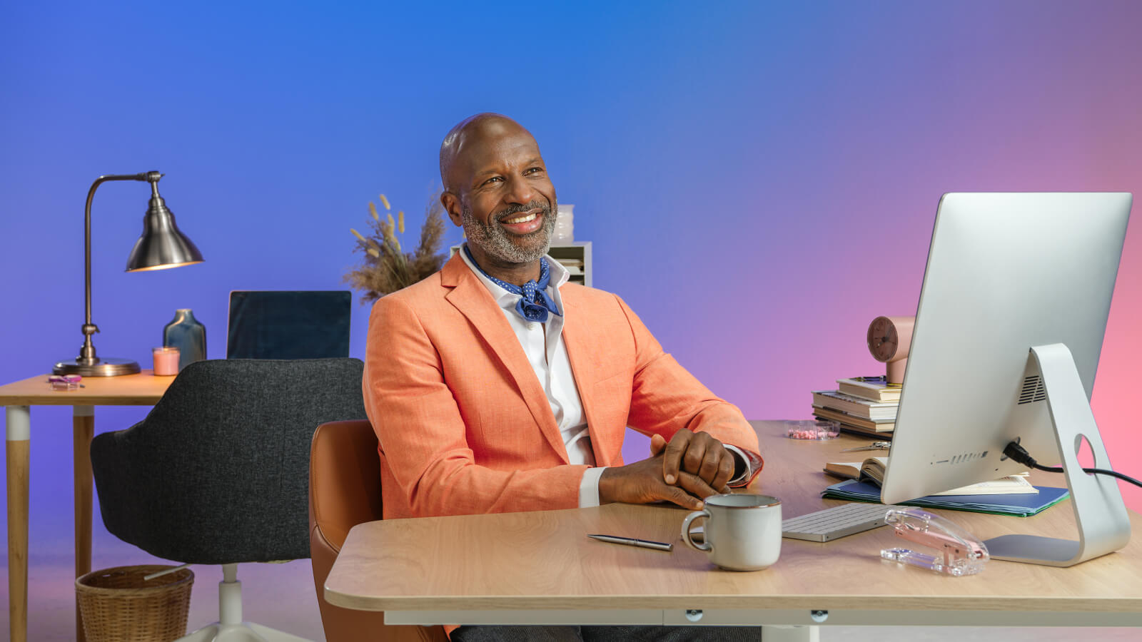 Man stood with arms folded in front of desk and computer
