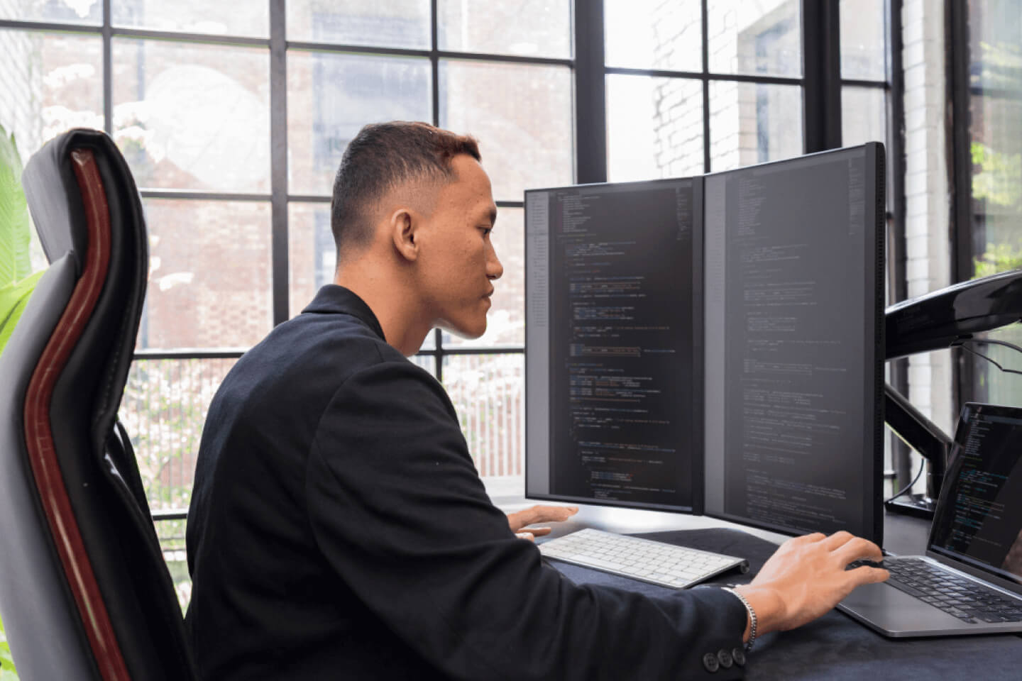 Technical expert reviewing code on multiple screens