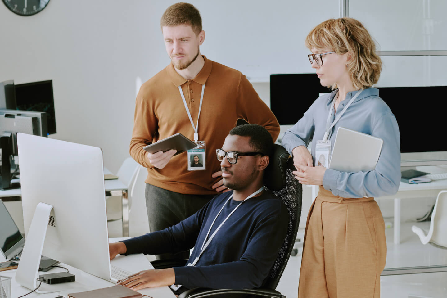 Three technical experts looking at computer screen in a modern office
