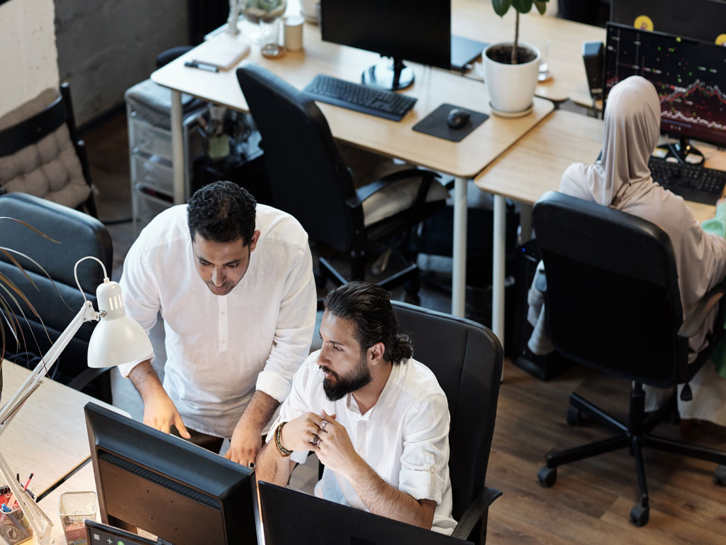 Two male colleagues working closely together in an office setting