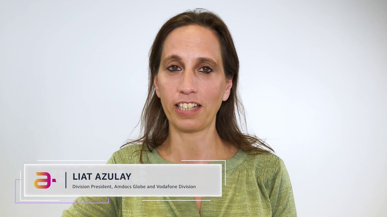 A woman in a green top is speaking in front of a neutral background. The on-screen label reads 'Liat Azulay, Division President, Amdocs Globe and Vodafone Division.'