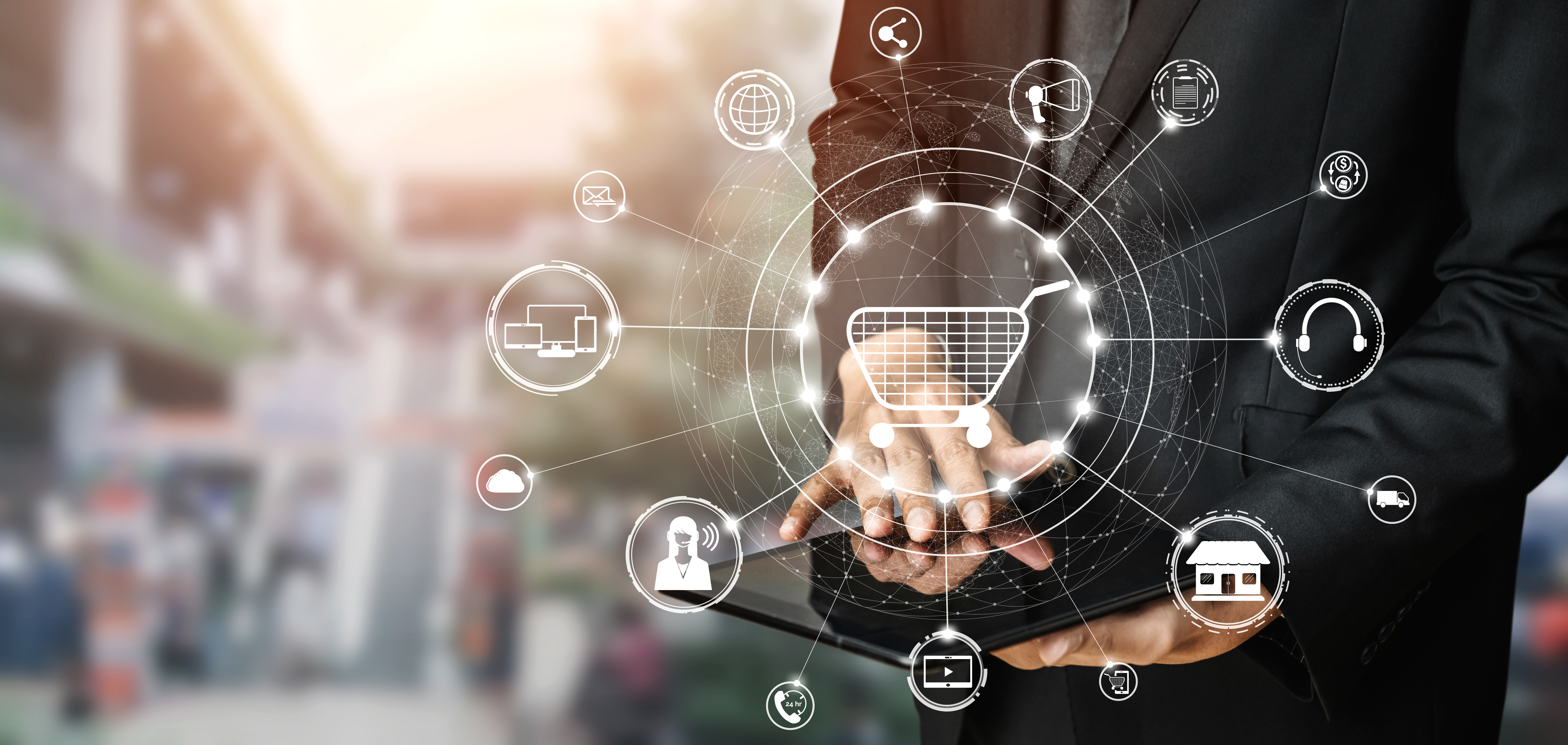 A businessman interacts with a tablet while a glowing digital shopping cart and various e-commerce and technology icons are overlaid, symbolizing modern digital retail solutions and omnichannel shopping.