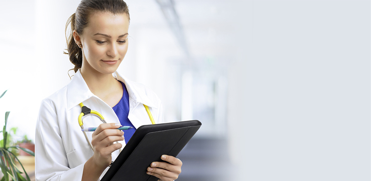 Smiling young female doctor/nurse examining the patient charts on hospital ward