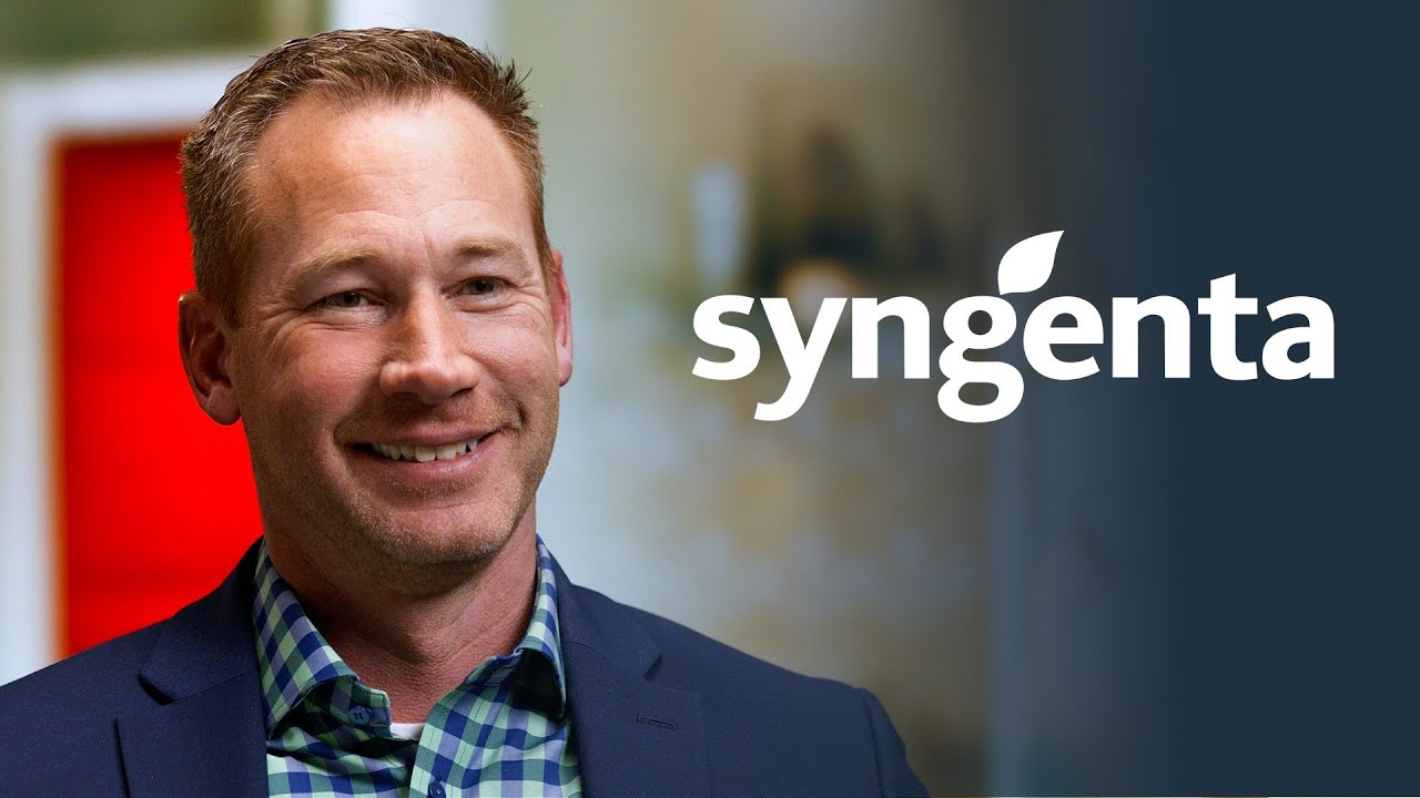 A YouTube video thumbnail featuring a smiling man in a blazer and checkered shirt, with the Syngenta company logo displayed prominently on a blurred background.