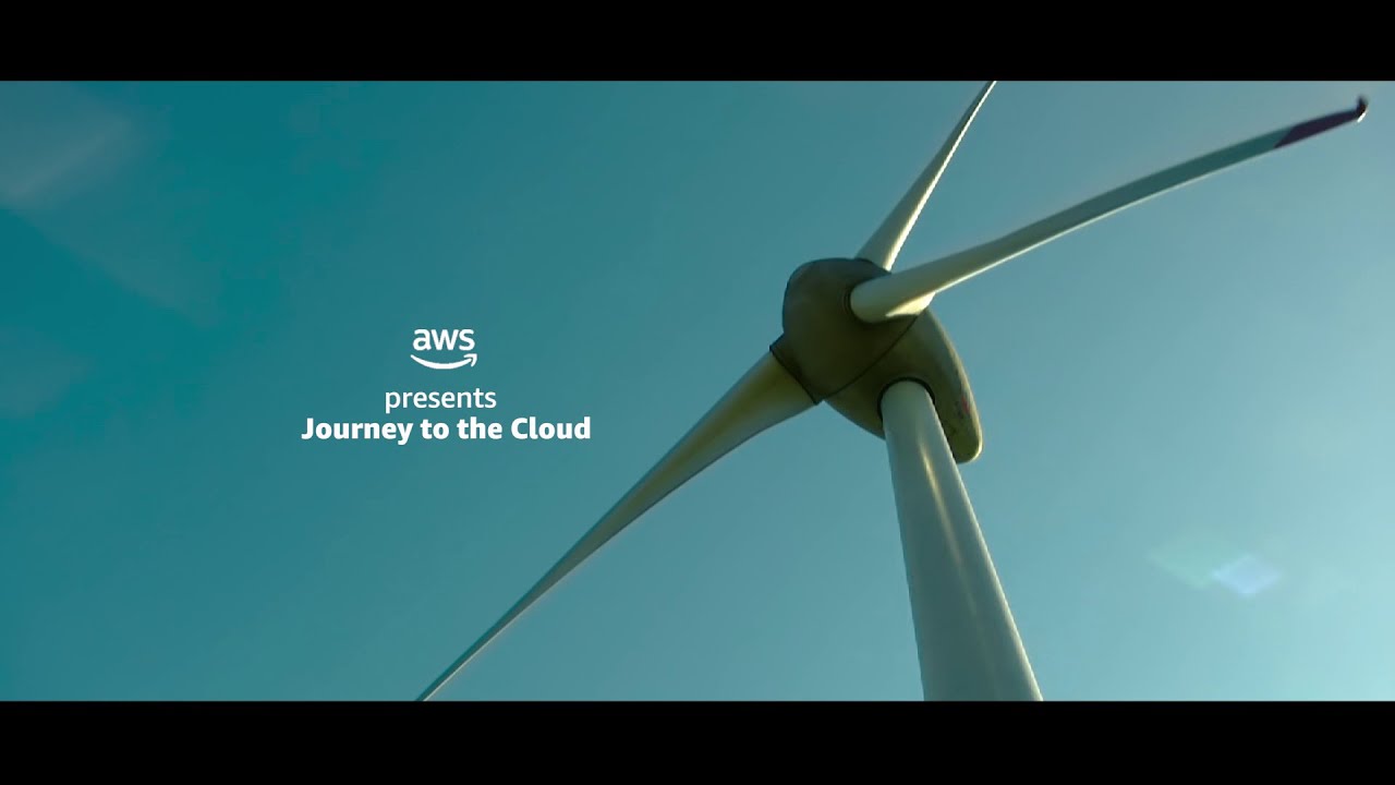 A low-angle view of a wind turbine set against a clear blue sky, with the text 'AWS presents Journey to the Cloud' displayed on the image.