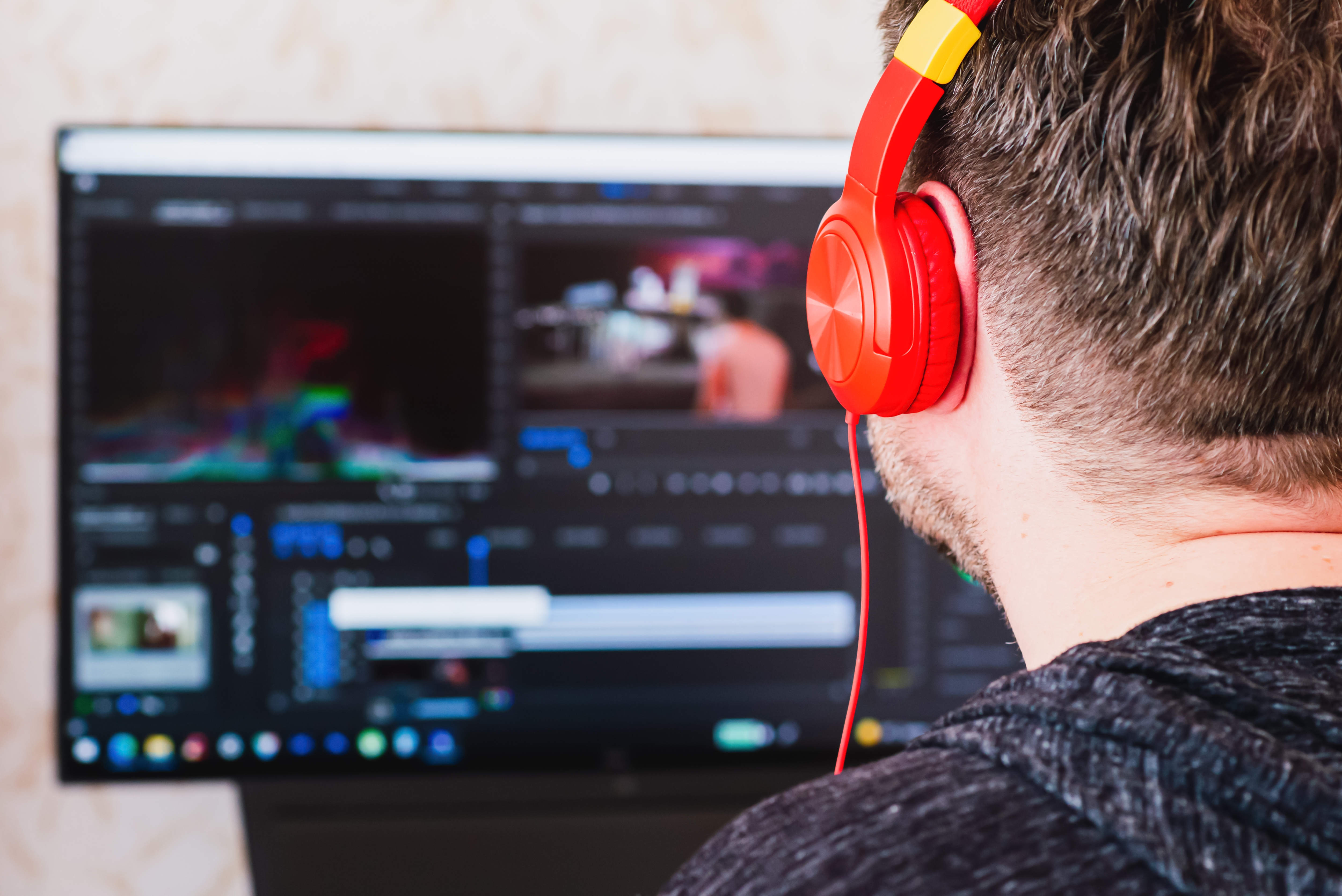 Freelancer wearing headphones editing video using postproduction software while working at home.Videographer processes the film movie editing on the computer. Selective focus,back view, copy space.; Shutterstock ID 2093492722; purchase_order: -; job: -; client: -; other: -