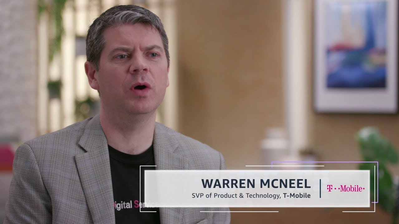 Warren McNeel, SVP of Product & Technology at T-Mobile, is speaking in a professional interview setting. The T-Mobile logo is visible, and the setting includes blurred office decor in the background.