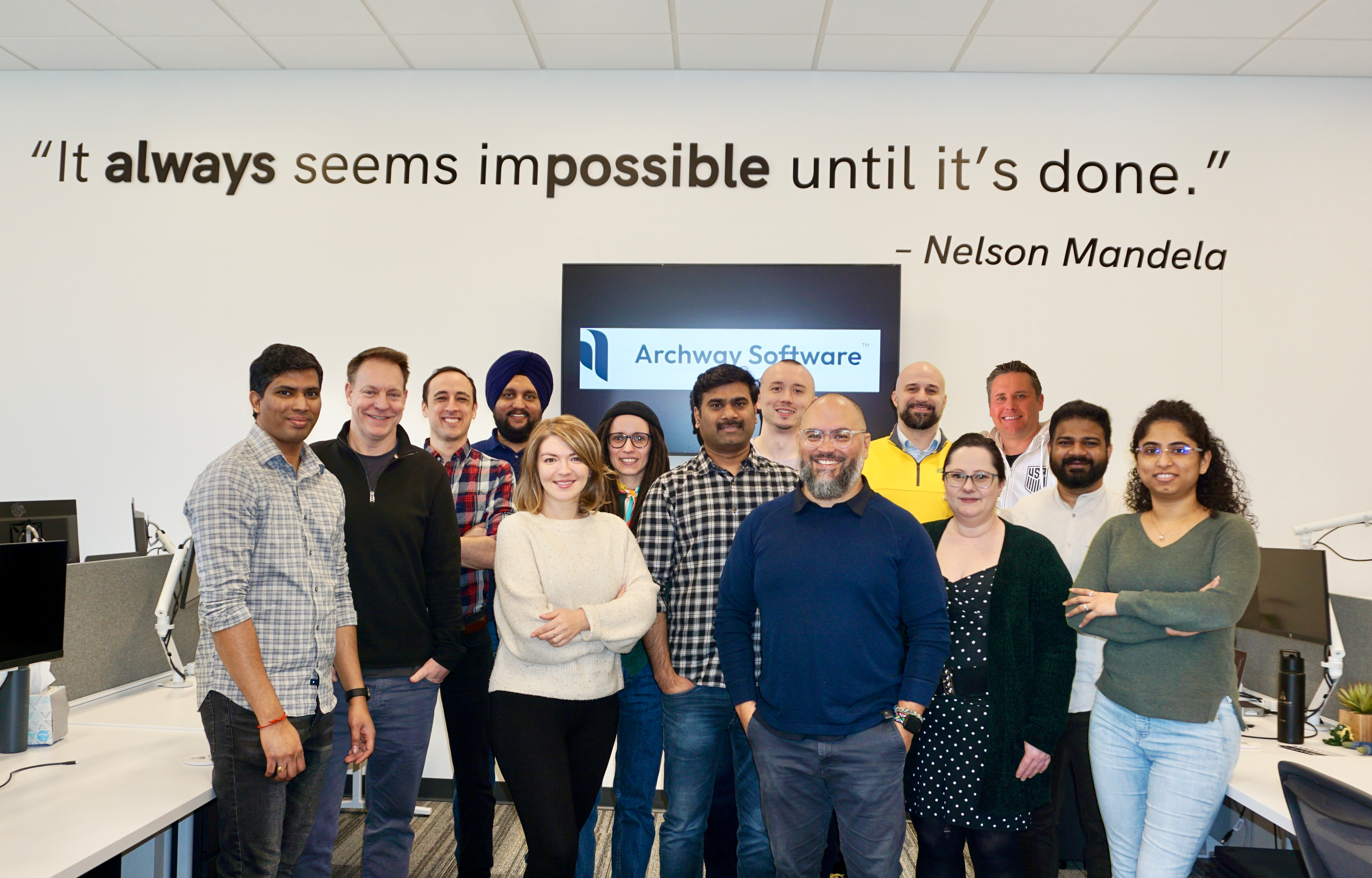 Group photo of the Archway Software team standing together in an office environment, beneath a wall quote by Nelson Mandela.