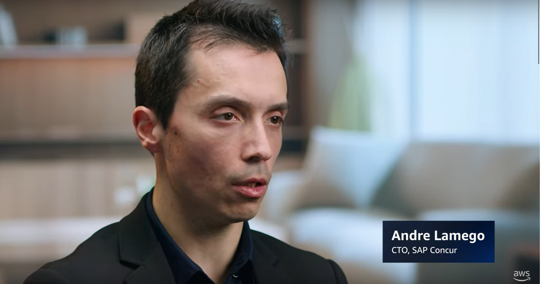Andre Lamego, CTO of SAP Concur, speaking in an interview setting with a blurred office background.
