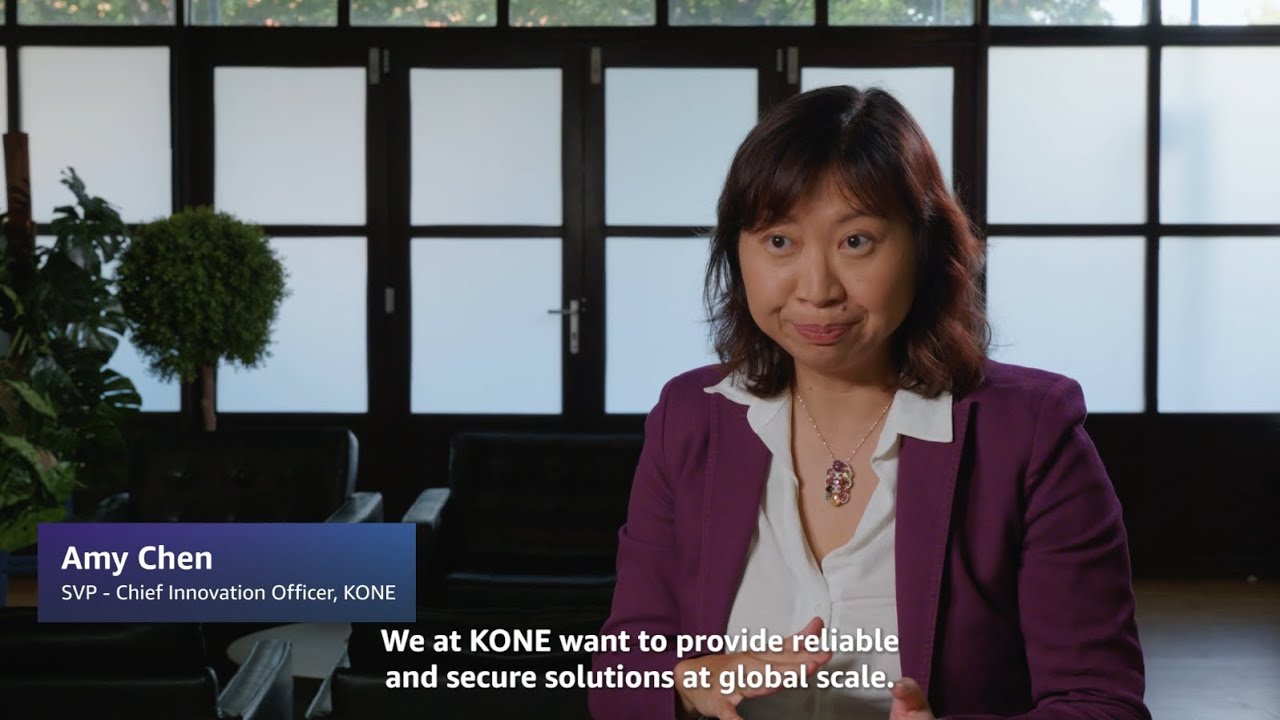 A person in a purple blazer sits in a modern office setting with plants and frosted windows, accompanied by text identifying Amy Chen as SVP - Chief Innovation Officer at KONE and a quote about providing reliable and secure global solutions.