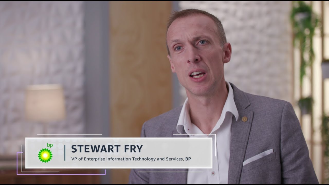 Screenshot of Stewart Fry, VP of Enterprise Information Technology and Services at BP, speaking during an interview. He is wearing a light grey suit and is standing indoors with a blurred background.