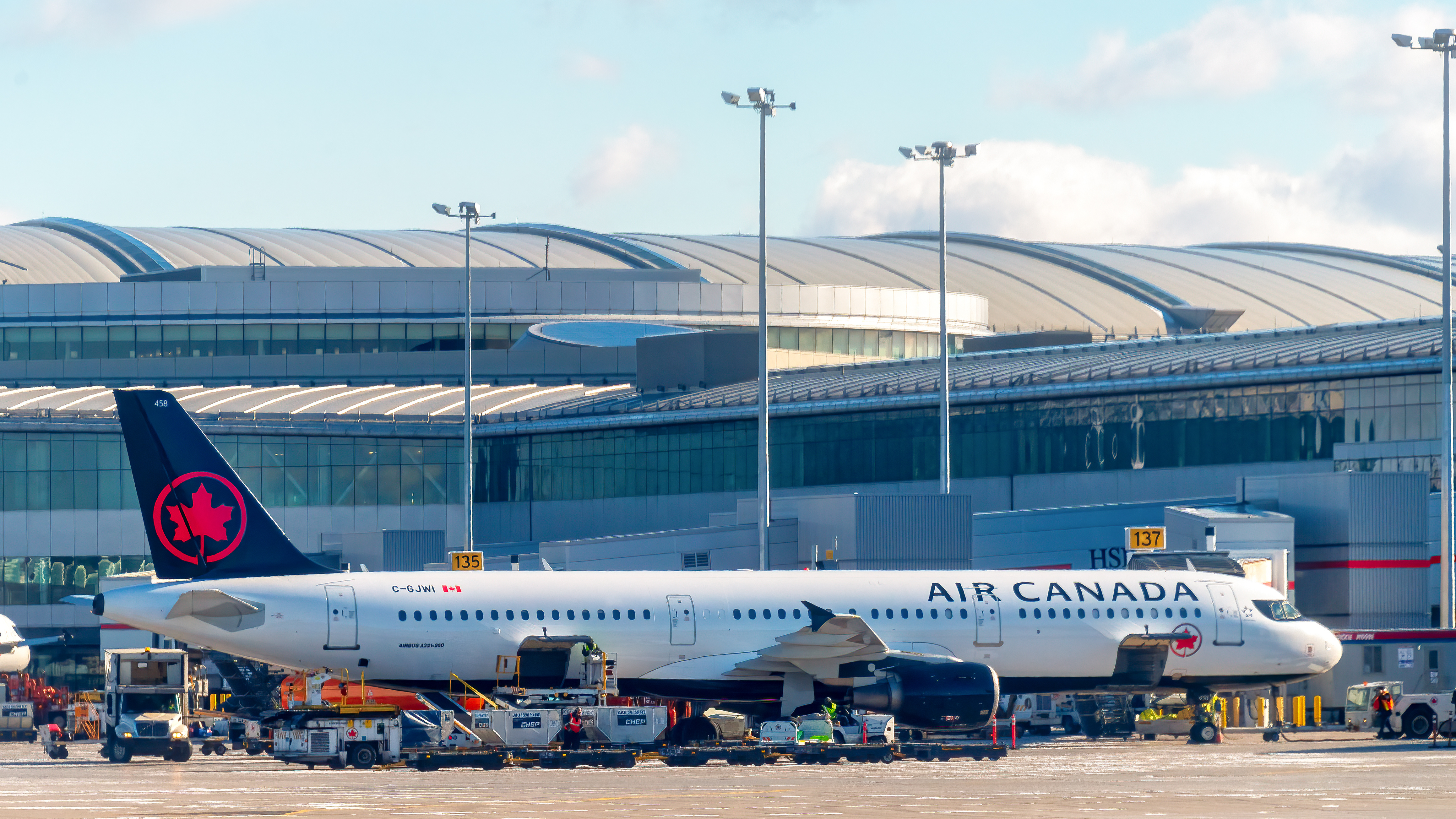 An Air Canada plane is seen in the boarding area at Pearson International Airport. The modern architecture of the terminal is seen in the background. The airport is the busiest and largest in the country.