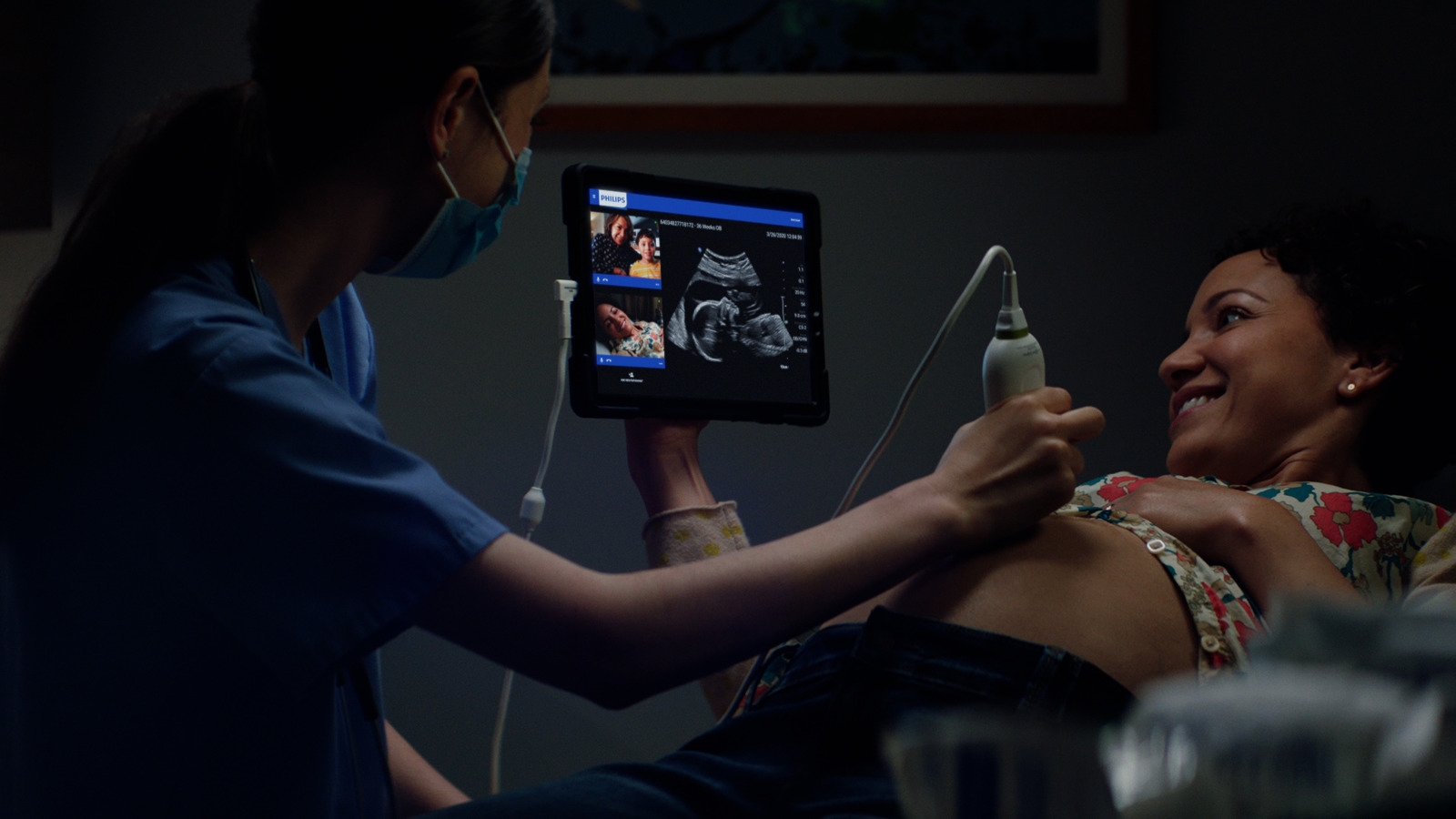 A clinician performs an ultrasound on a patient while sharing the live imaging on a handheld tablet