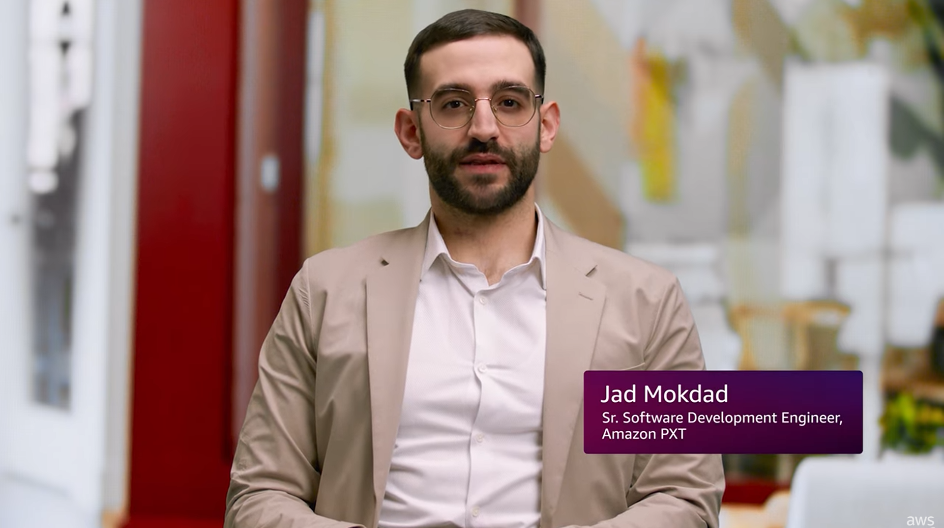 A testimonial image featuring a person identified as a Sr. Software Development Engineer at Amazon PXT, associated with scaling hiring processes using Amazon Connect. The background is an office setting with blurred decor, and the subject is wearing glasses, a light-colored blazer, and a white shirt.