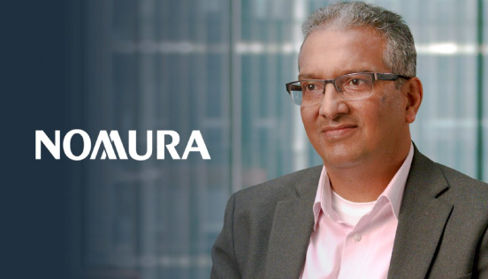 The Nomura logo displayed next to a person in a suit and pink shirt, with a blurred office background.