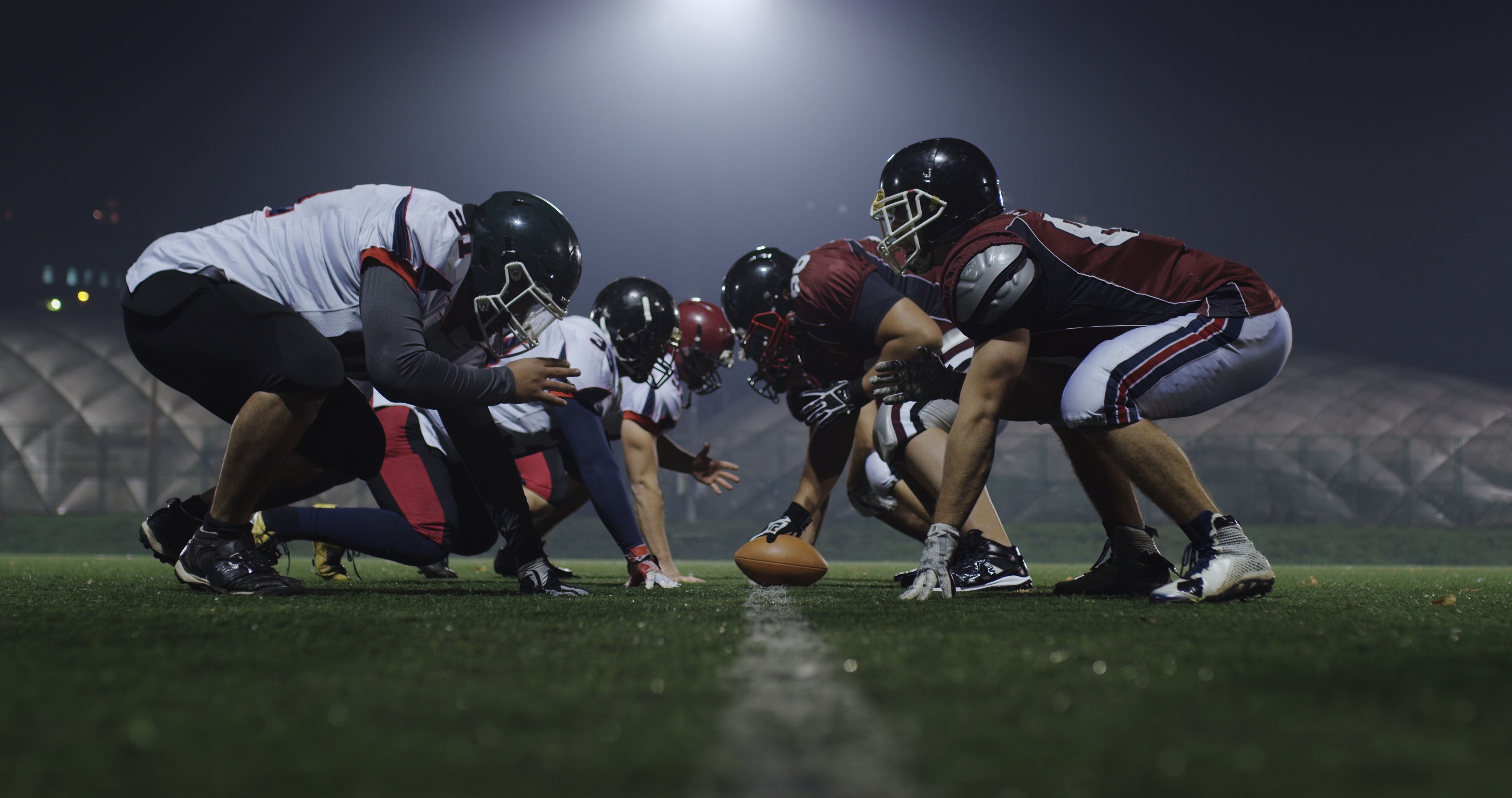 american football players are ready to start on field at night