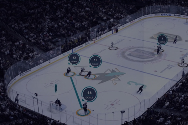 A professional ice hockey game in a large arena with player statistics and goal information overlaid on the ice, highlighting goals scored by multiple players.