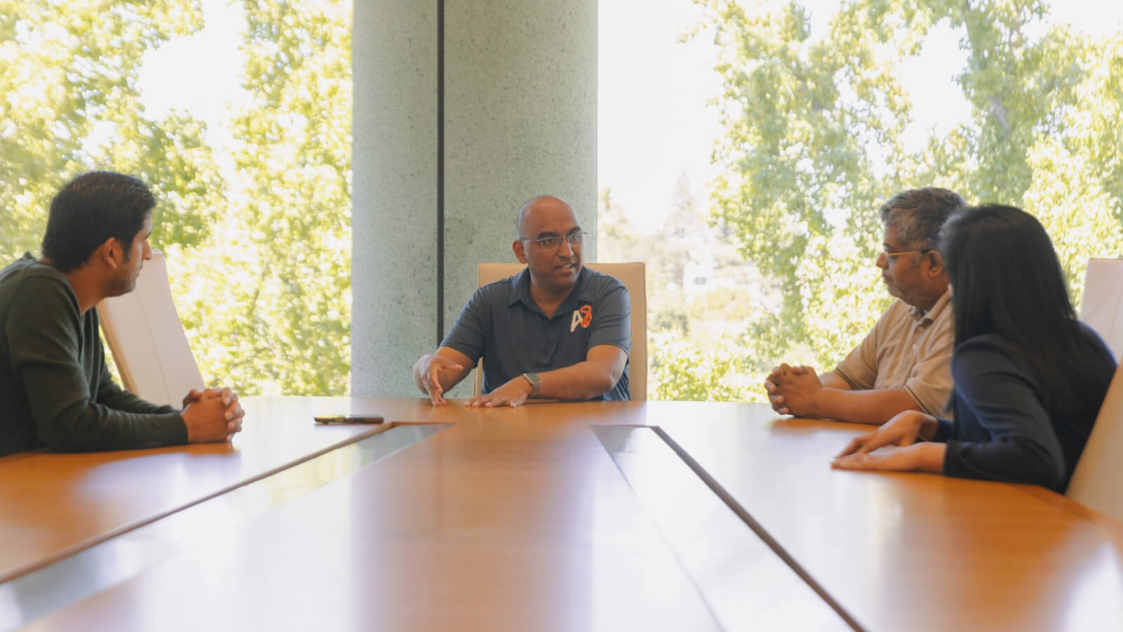Articul8 team gathered around a meeting table in front of large windows overlooking outdoor greenery