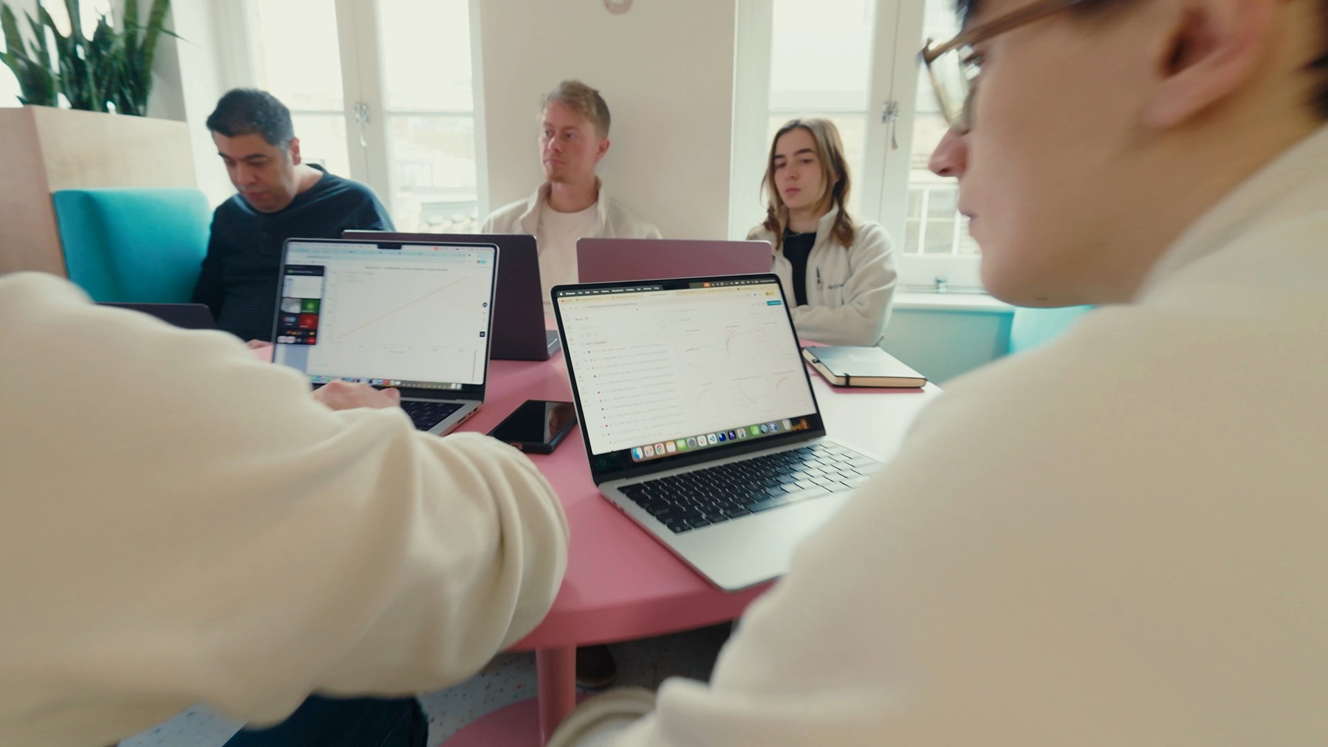 Helical team members collaborating around laptops at a desk in the office