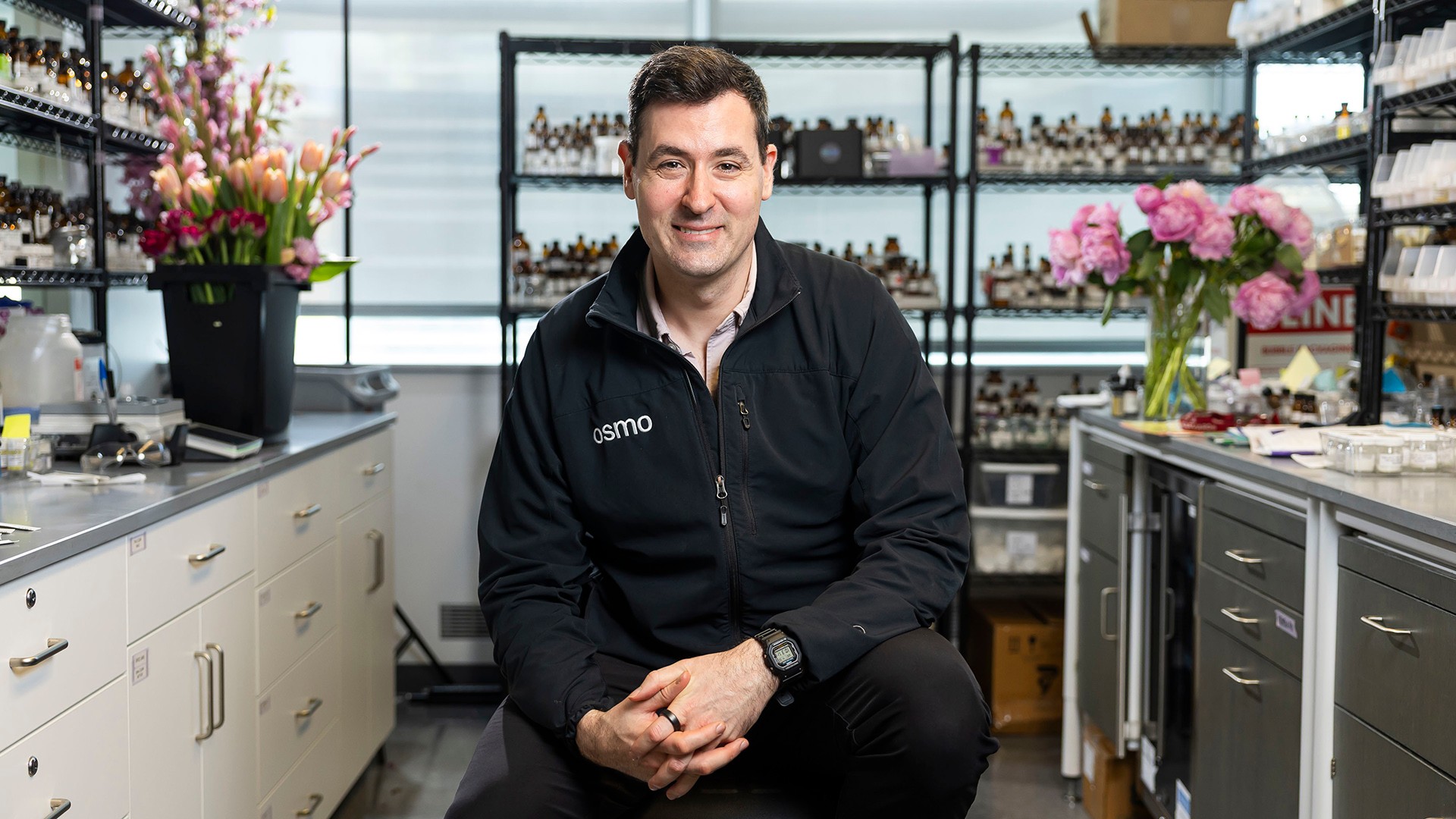 Osmo CEO Alex Wiltschko seated in a fragrance lab surrounded by flowers and scent samples