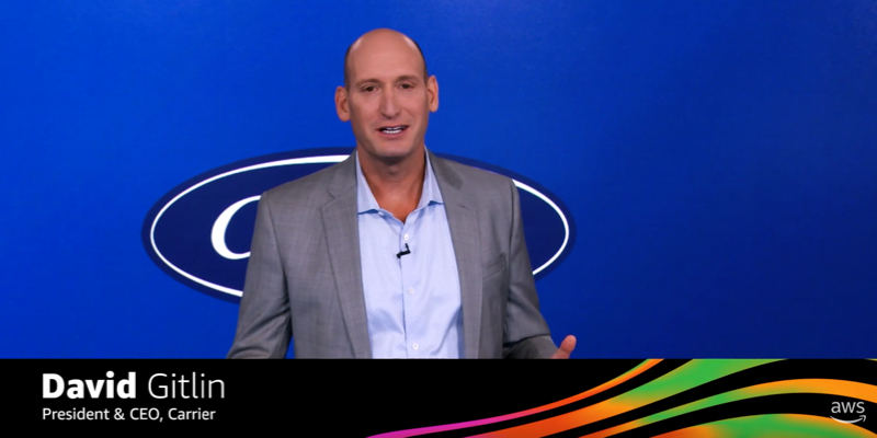 David Gitlin, President & CEO of Carrier, speaking in front of a blue background with a logo, at an AWS event.