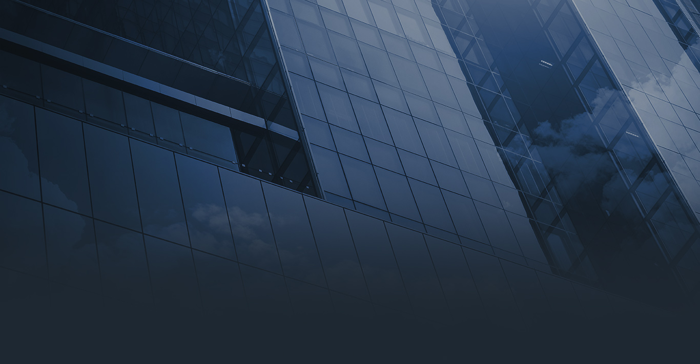 A modern glass building reflecting clouds in its windows.