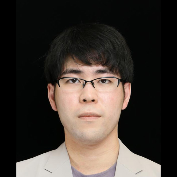 A portrait photograph of a man wearing glasses, pictured against a black background.