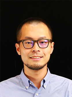 Portrait headshot of a man in glasses and a light blue shirt, on black background