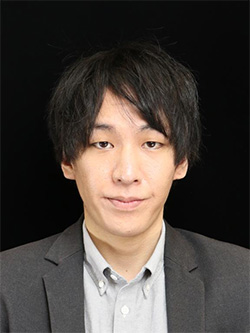 A portrait of a man with short dark hair wearing a suit jacket and collared shirt against a black background.
