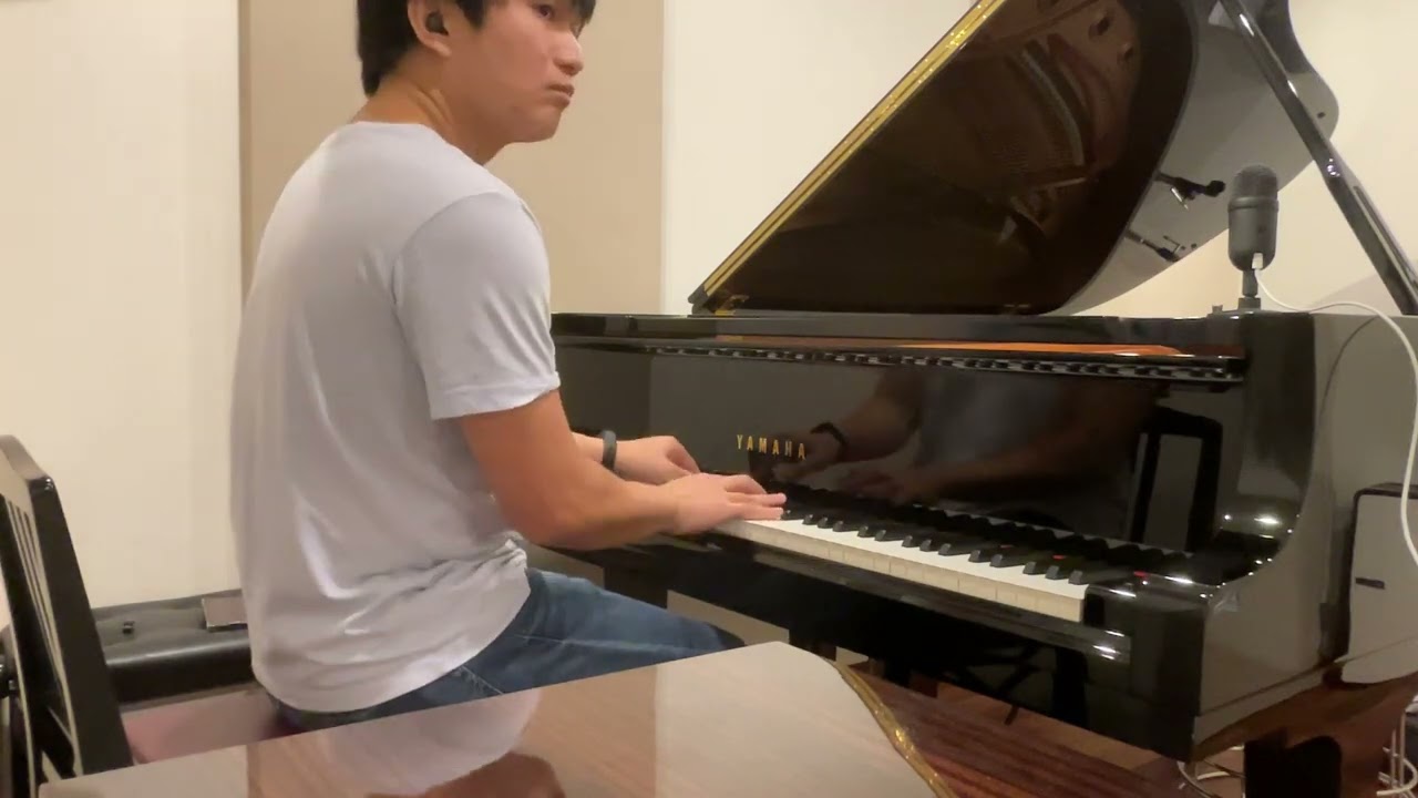 A man playing a Yamaha grand piano in a modern indoor setting.