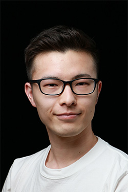 A portrait photo of a person wearing a white shirt and glasses, with a dark background.