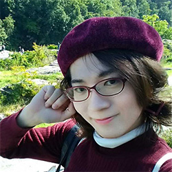 A person wearing glasses and a burgundy beret smiling outdoors, with greenery in the background. Profile photo style.