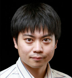 Portrait of an individual with short dark hair and a striped shirt, facing the camera, against a black background.