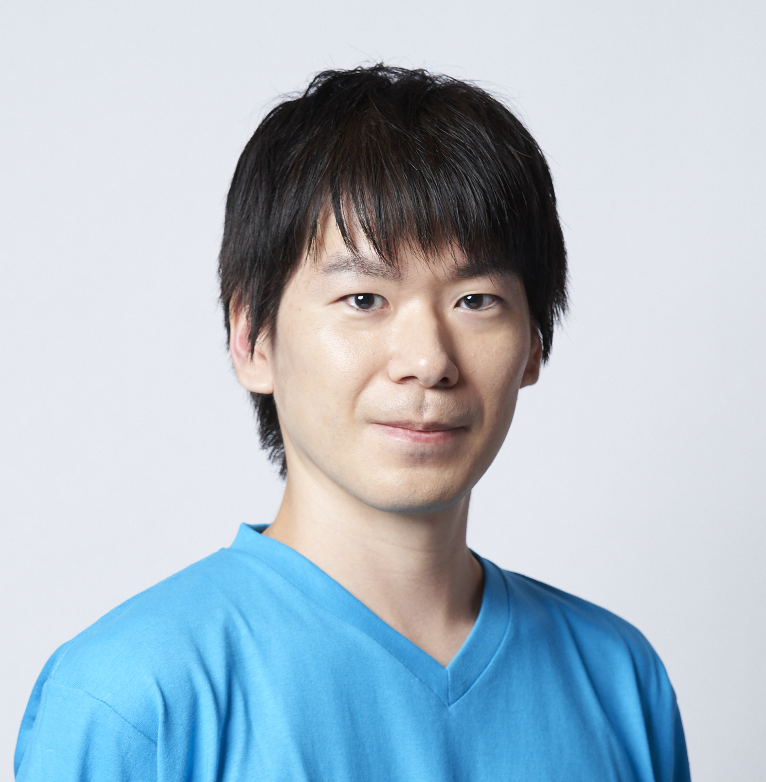 Portrait of an Asian man wearing a blue shirt, photographed against a plain light background.