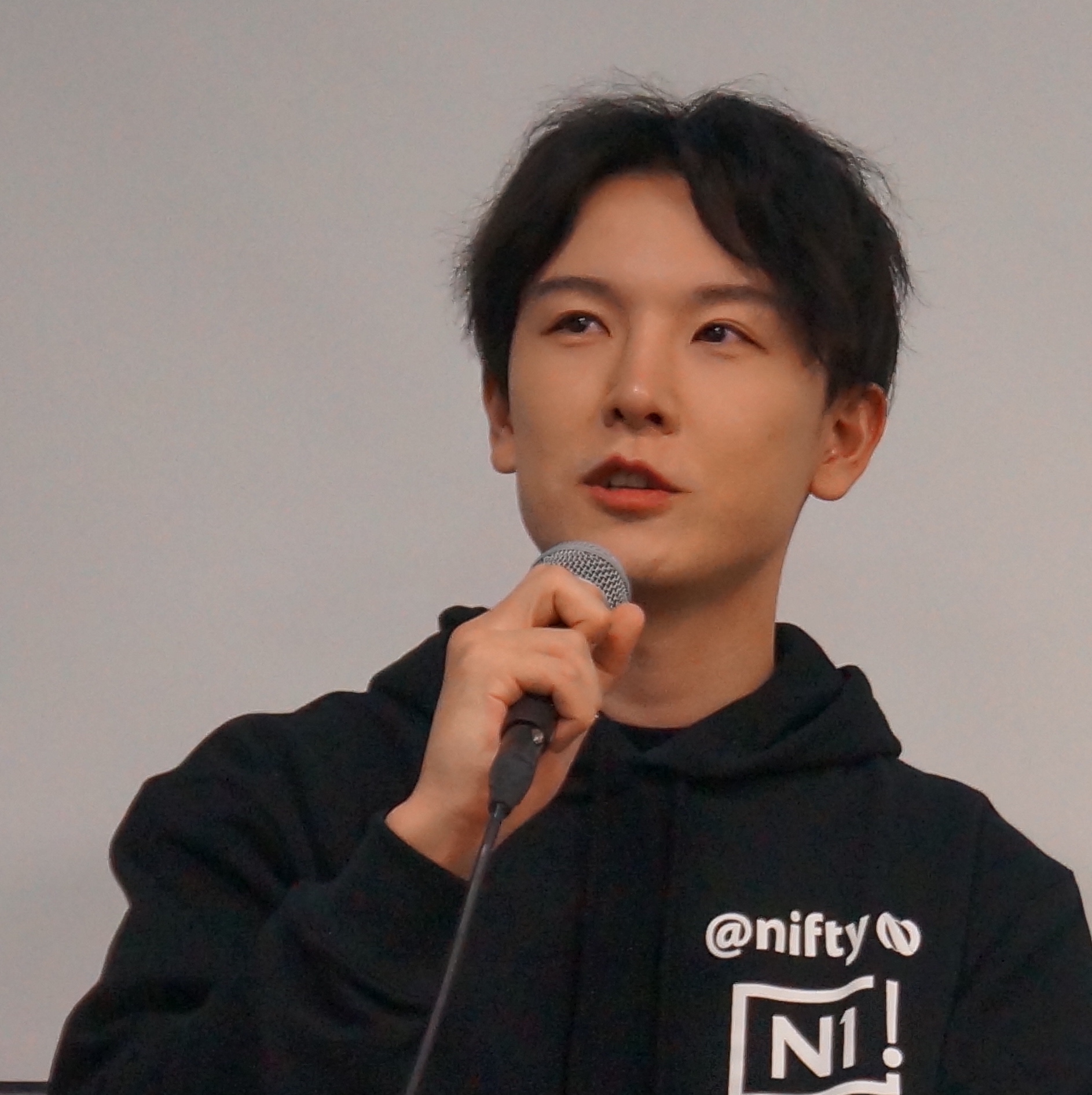 A person wearing a black hoodie with 'Nifty' branding is speaking into a microphone.