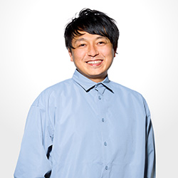 A portrait photograph of a person smiling and wearing a blue shirt, set against a plain white background.