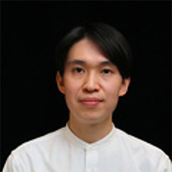 Portrait photo of an individual wearing a white formal shirt against a black background.